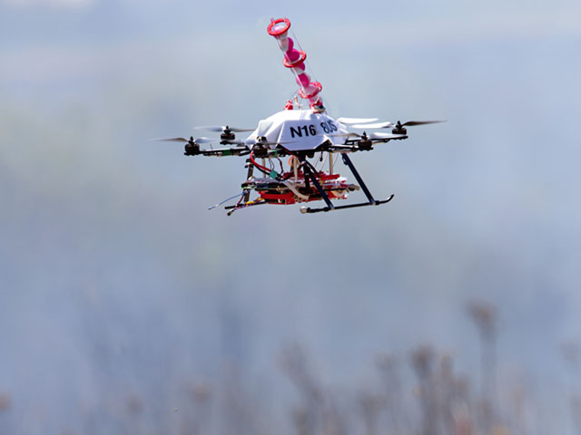 Engineers at the University of Nebraska-Lincoln have developed a drone able to light controlled prairie burns using balls dropped from the sky. The drone injects a liquid into the plastic spheres to start a delayed fiery process so the balls can fall to the ground before igniting. (Photo by Craig Chandler, University Communications, University of Nebraska-Lincoln)